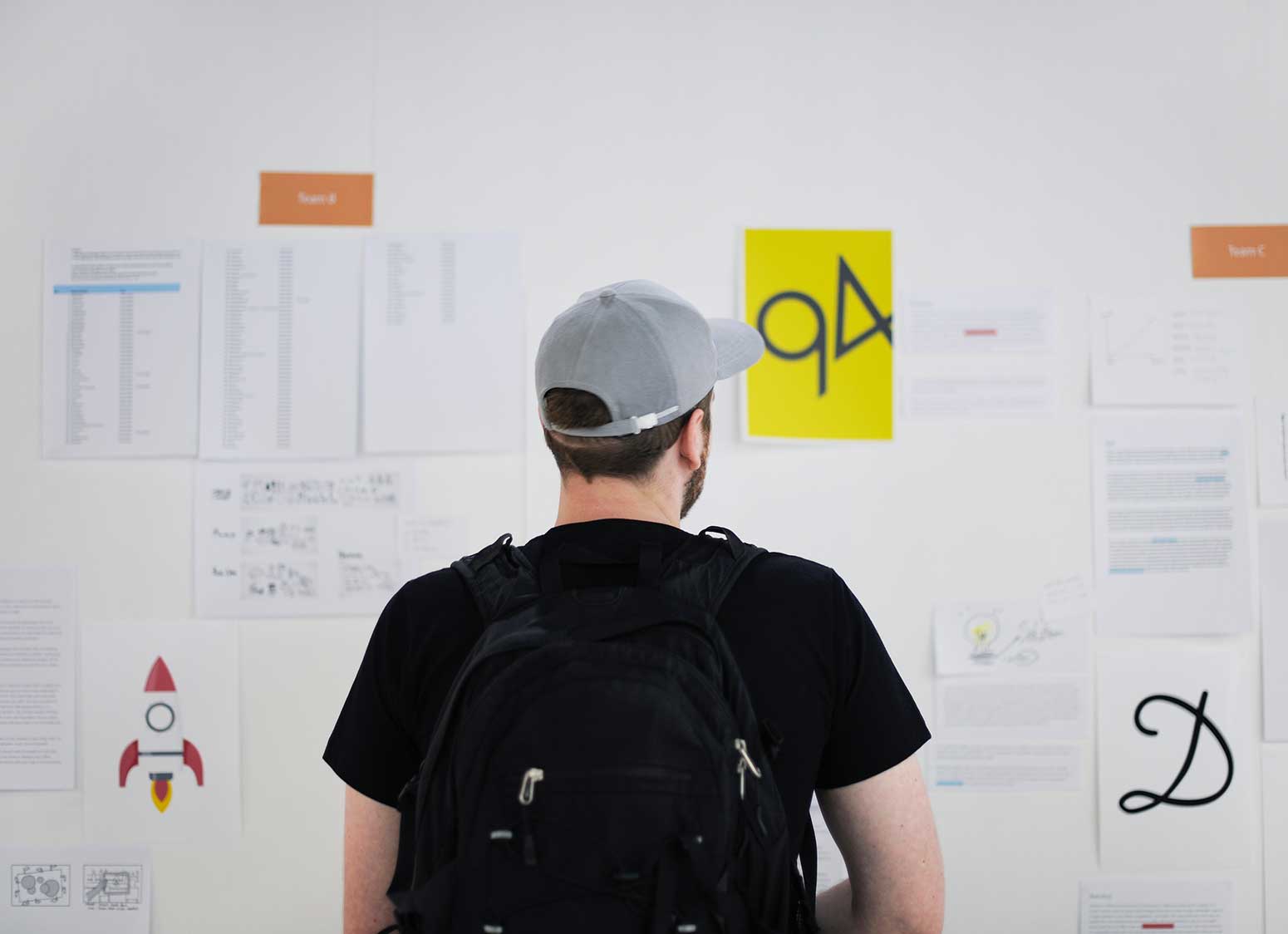 man with backpack observing notes on wall