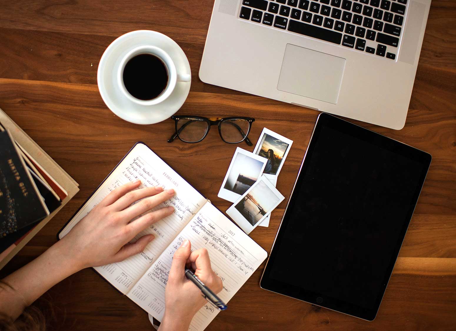 woman taking notes at desk with laptop and tablet